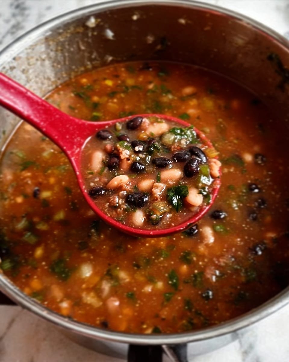 A large silver pot filled with thick soup that has a reddish-brown broth. Floating inside are small pieces of white beans, black beans, and bits of green herbs mixed with tiny bits of meat. A red spoon holds a scoop of the soup above the pot, showing the mix of beans, chopped greens, and small chunks of meat clearly. The soup looks hearty and rich. The image has a white marbled background. Photo taken with an iphone --ar 4:5 --v 7