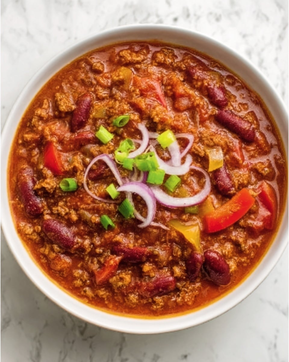 A white bowl filled with thick chili, showing three main layers: a base of chunky red tomato sauce mixed with brown cooked ground meat, scattered dark red kidney beans, and soft pieces of yellow and red bell peppers. On top, there are three thin rings of light purple onion and small green onion pieces clustered in the center. The bowl sits on a white marbled surface. photo taken with an iphone --ar 4:5 --v 7