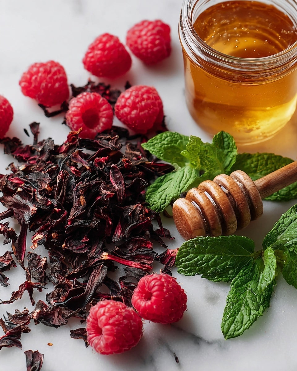 The image shows a close-up of fresh red raspberries scattered on a white marbled surface mixed with dark, dried hibiscus petals that have a rough, curled texture. Nearby, bright green mint leaves with visible veins and a slightly rough texture lie flat on the same surface. On the right side, there is a glass jar filled with golden honey, with a wooden honey dipper partially dipped inside, showing honey clinging softly to its grooves. The whole setup has a fresh and natural feel with a mix of red, green, dark brown, and golden colors. Photo taken with an iphone --ar 4:5 --v 7