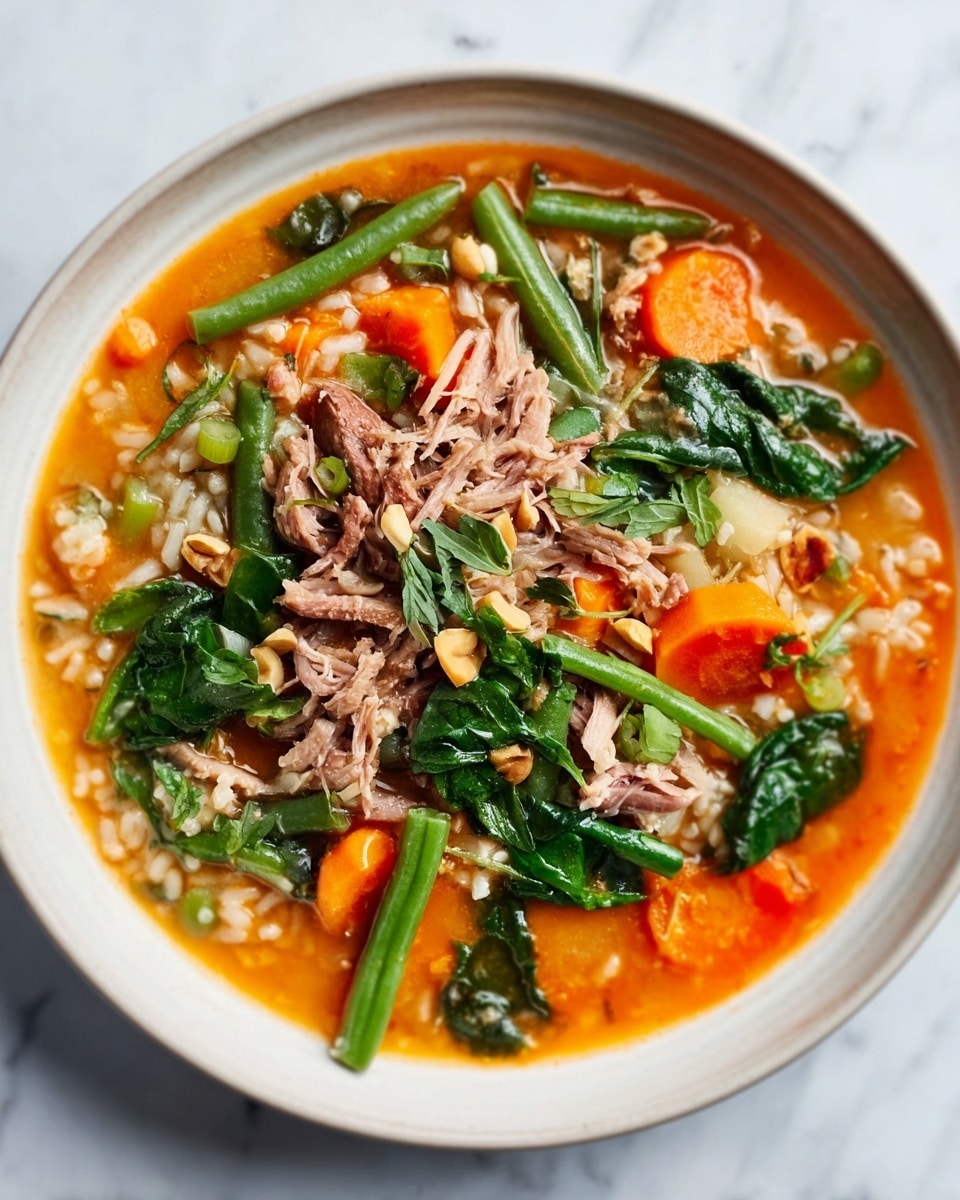 A white bowl filled with thick, brown soup with visible chunks of meat and small diced vegetables like celery and carrots floating throughout. A metal spoon is resting inside the bowl, partially submerged in the soup. The bowl sits on a white marbled surface, with some lemon slices and a small silver spoon just nearby. photo taken with an iphone --ar 4:5 --v 7