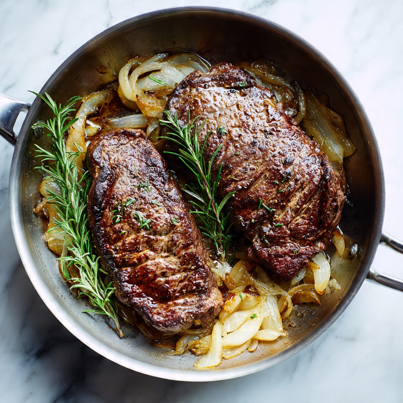 The image shows a metal pan filled with two cooked steaks that have a dark brown, crispy crust on the outside. Below the steaks, there is a layer of light golden sliced onions, slightly soft and cooked. A sprig of fresh green rosemary rests against the side of the pan. The pan is set on a white marbled surface. The lighting highlights the meat's texture and juicy look. Photo taken with an iphone --ar 4:5 --v 7
