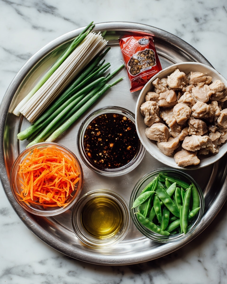 A silver metal tray holds several cooking ingredients on a white marbled surface: at the top left is a red package of soba rice noodles standing upright, next to three green onions lying horizontally. Below the onions is a small clear jar filled with a dark sauce containing visible spices. Centrally placed on the tray is a white bowl filled with chunks of light brown marinated meat. Around it are three small clear glass bowls, one with bright orange shredded carrots on the bottom right, one with fresh green snap peas below the meat bowl, and two smaller bowls on the bottom left that contain light golden oil and a minced garlic mixture. photo taken with an iphone --ar 4:5 --v 7