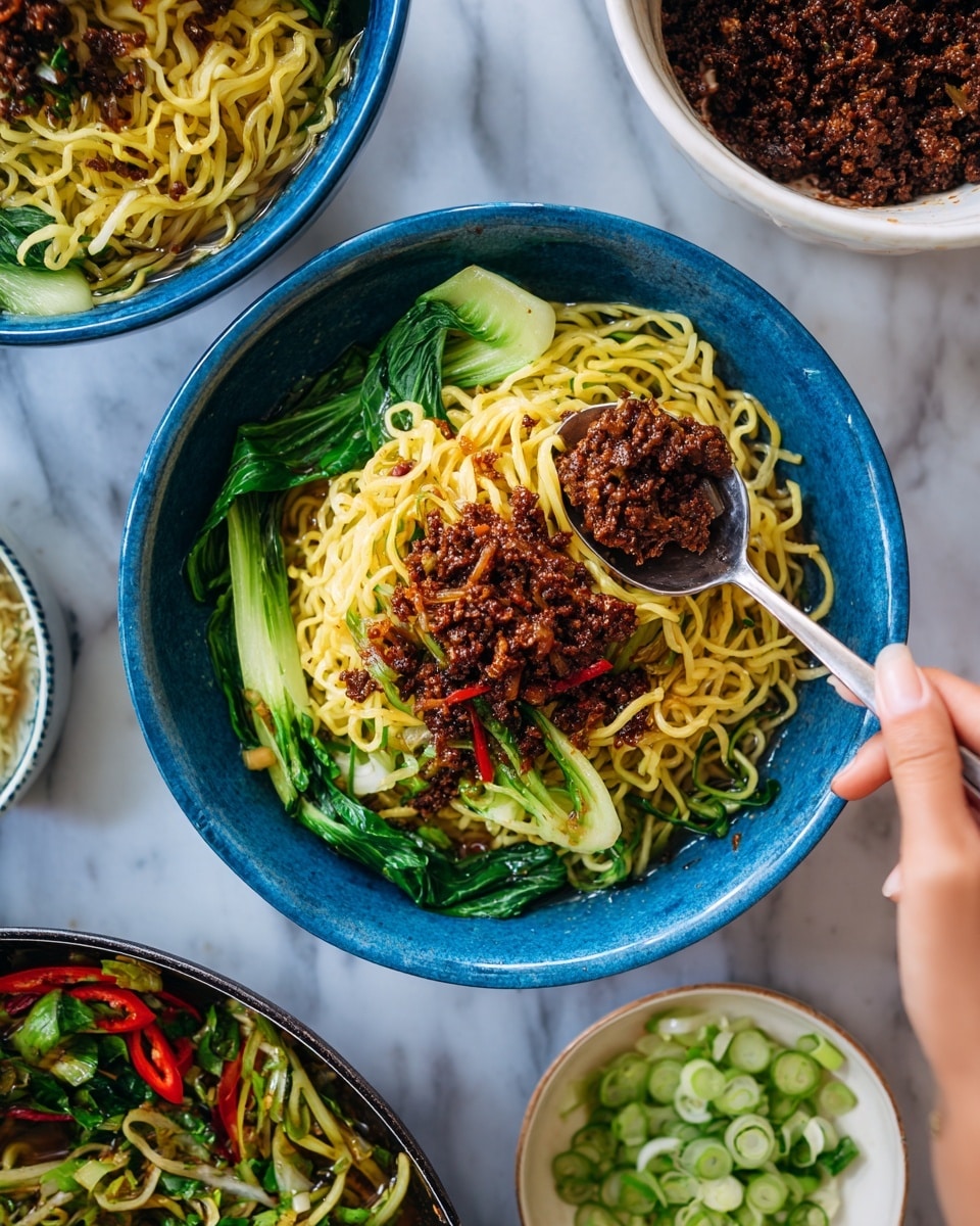 The image shows a blue bowl filled with two main layers: on the bottom, yellow noodles mixed with bright red bell pepper strips and green leafy vegetables, and on the top, a generous layer of dark brown cooked minced meat. A woman's hand holding a spoon is placing some minced meat on the noodles. Surrounding the bowl are parts of other blue bowls with similar noodle and meat contents, a white bowl full of dark minced meat, and a small white bowl with finely sliced green onions. The surface beneath everything is a white marbled texture. photo taken with an iphone --ar 4:5 --v 7