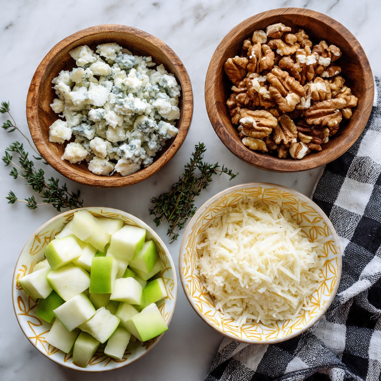 Four small wooden bowls and white bowls are placed on a white marbled surface. One wooden bowl is filled with finely crumbled blue cheese, showing a mix of white and blue-green textures. Another wooden bowl holds light brown walnut halves with a rough texture. Two white bowls with yellow geometric patterns contain diced green apples with shiny smooth surfaces, and white grated cheese with a fluffy, powdery look. Sprigs of fresh green thyme lie between the bowls, and a black and white checkered cloth is partially visible on the bottom right corner. Photo taken with an iphone --ar 4:5 --v 7