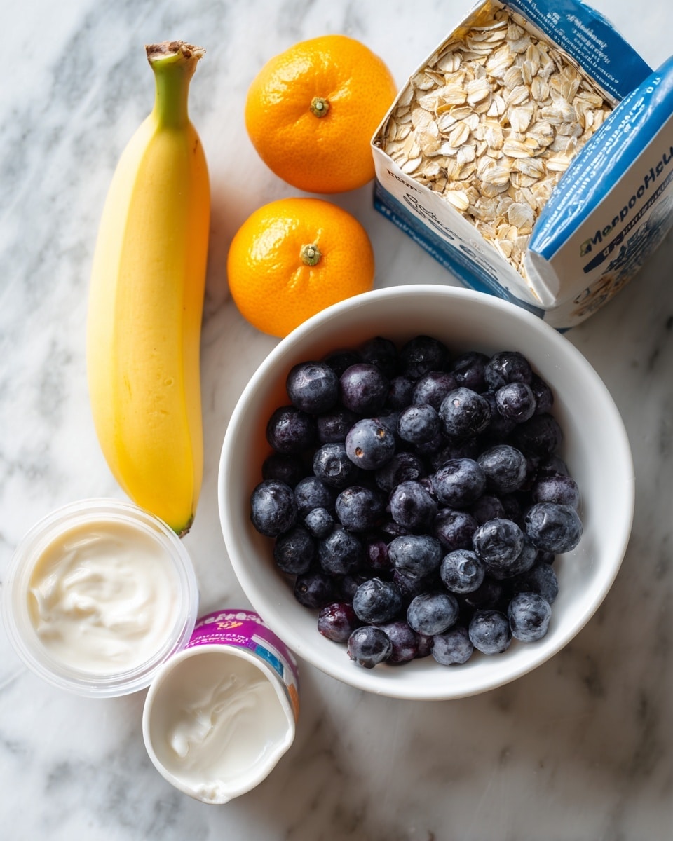 The image shows a white bowl filled with small dark blueberries and blackberries on a white marbled surface. Next to the bowl, there is a banana with a green tip resting diagonally. Above the banana, there is a white measuring cup filled with round oats. To the left of the oats, two small orange kumquats are placed close together. Below the kumquats are two yogurt containers, one of them is white with a colored lid and the other white with black text on the side. Behind the items, a blue and white cereal box is standing, showing some oats on the packaging. The photo was taken with an iphone --ar 4:5 --v 7
