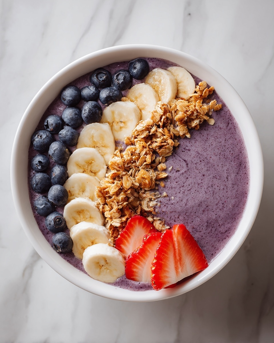 A white bowl filled with a thick purple smoothie base in the center, topped with a row of fresh blueberries on the left edge, a cluster of light brown granola on the top right, several thin banana slices neatly arranged along the bottom edge, and a few sliced strawberries fanned out above the granola near the top edge. The bowl sits on a white marbled surface. Photo taken with an iphone --ar 4:5 --v 7