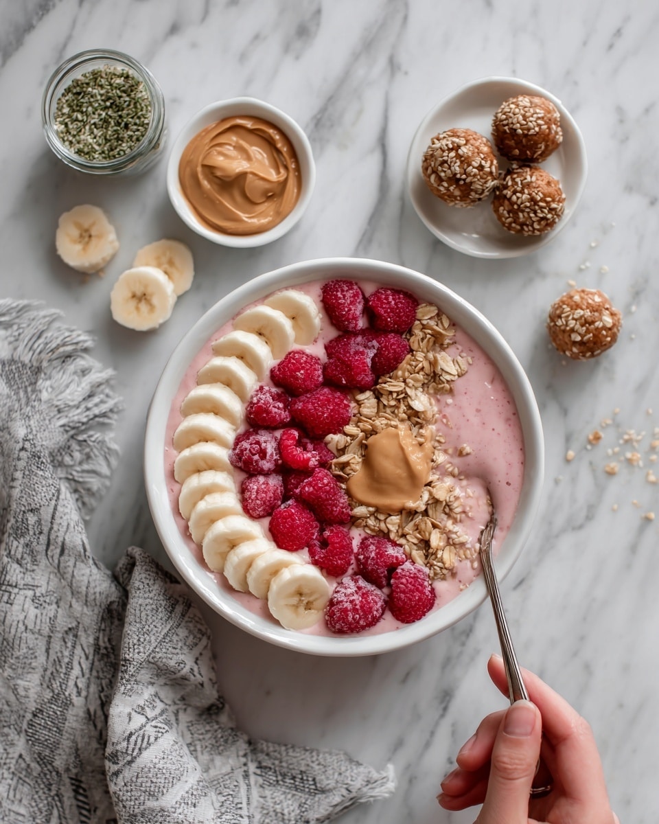 The image shows a white bowl filled with a pink smoothie base, topped with banana slices arranged in a row on one side, a cluster of bright red raspberries on another side, a spoonful of peanut butter, and a sprinkle of granola placed in the center. Around the bowl, there are small white dishes with more banana slices, extra raspberries, and round energy bites. A small clear container of hemp seeds and a white bowl with peanut butter are also visible on a white marbled surface. A woman's hand holds a spoon dipping into the smoothie bowl. A gray and white patterned cloth is partially shown near the bowl photo taken with an iphone --ar 4:5 --v 7
