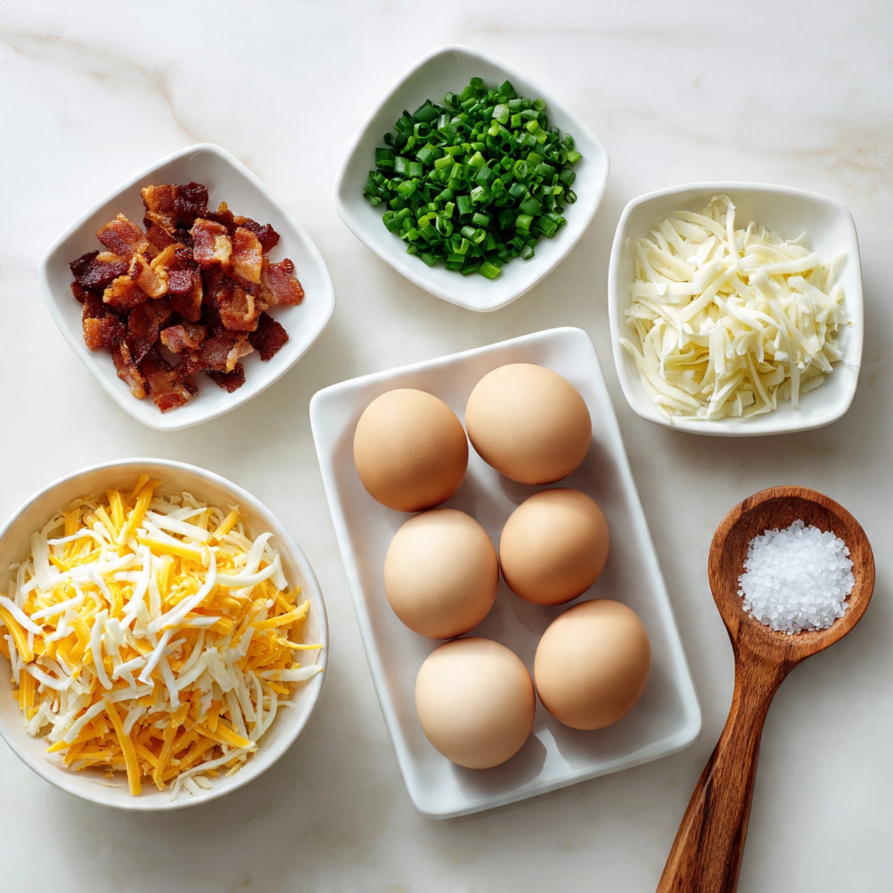 The image shows five ingredients arranged on a white marbled surface. At the center is a white tray holding six light brown eggs. Above the eggs to the left is a small white square dish filled with crispy cooked bacon pieces, and to the right is another small white square dish containing chopped green chives. At the bottom left is a white round bowl filled with a mix of shredded yellow and white cheese. On the bottom right is a small wooden spoon holding a small pile of white salt. The arrangement is clean and organized with soft lighting, photo taken with an iphone --ar 4:5 --v 7