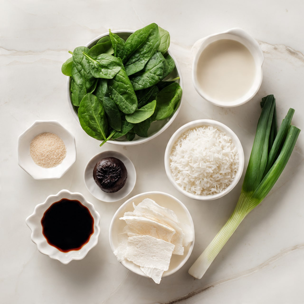 The image shows seven items arranged on a white marbled surface. At the top left, there is a white bowl filled with fresh green spinach leaves. To the right, a white bowl contains a light creamy liquid. Below it, a single green onion with a bright green stalk stretches diagonally across the bottom right corner. In the center, there is a white bowl holding fluffy white rice. Below the rice, another white bowl contains thin pale tofu skin sheets, slightly folded. To its right, a small white dish holds a dark brown shiitake mushroom. Below that, a small white scalloped dish contains a dark soy sauce. At the top left, a small white dish holds a light beige powder. The composition is neat and clear. photo taken with an iphone --ar 4:5 --v 7