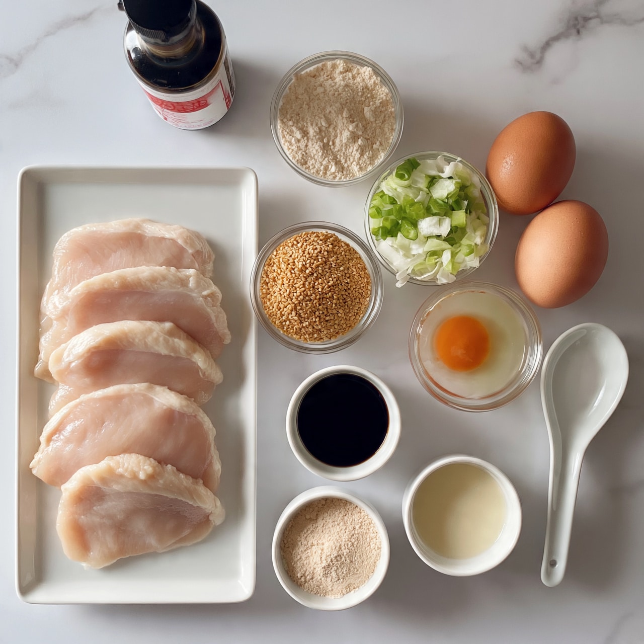 square image The image shows raw ingredients arranged neatly on a white marbled surface. On the left is a white rectangular plate holding four pale pink slices of raw chicken. Above it is a small dark bottle with a red and white label. To the right are small clear glass bowls filled with light beige flour, golden sesame seeds, and chopped green onions mixed with sliced white cabbage. Two brown eggs rest next to these bowls. One small bowl contains a bright orange egg yolk in clear egg white. Below them are small round white bowls filled with dark soy sauce, light beige powder, and light cream liquid. A white ceramic spoon lies on the surface near the eggs. The overall colors are light and natural, with a clean and organized look photo taken with an iphone --ar 4:5 --v 7