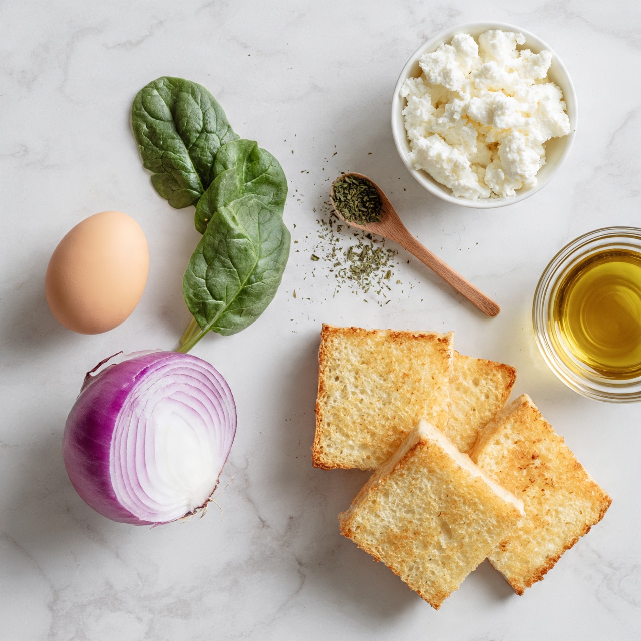 square image VThe image shows fresh ingredients on a white marbled surface. On the left, there is a light brown whole egg and a half of a purple onion with white inside. Next to them, there is a small bunch of green spinach leaves with a smooth texture. On the top right, there is a small white bowl filled with white crumbly cheese. Nearby, a small wooden spoon holds some dried green herbs, with more herbs scattered on the surface. At the bottom right, four square pieces of light golden-brown toasted bread are stacked slightly overlapping. Finally, a small clear glass bowl filled with golden olive oil is placed on the far right. photo taken with an iphone --ar 4:5 --v 7