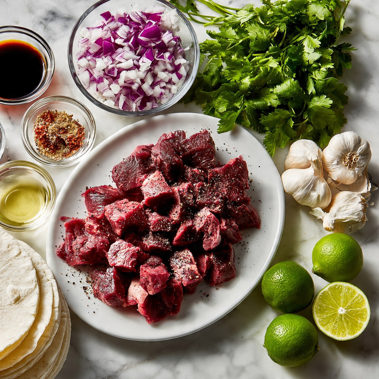 square image A white oval plate holds a layer of small, uneven pieces of raw, red meat with some black pepper and seasoning sprinkled on top. Above the plate, a clear glass bowl is filled with finely chopped purple and white onions. To the right, a bunch of fresh green cilantro lies on the white marbled surface. There are small clear bowls holding dark brown soy sauce, a mix of ground spices with reddish and light brown colors, and a light yellow oil. Next to them, there is a cluster of white garlic cloves. Toward the bottom right, there are three whole green limes and one lime cut in half showing the bright green inside. At the bottom left, a stack of soft white corn tortillas rests on the white marbled surface. photo taken with an iphone --ar 4:5 --v 7