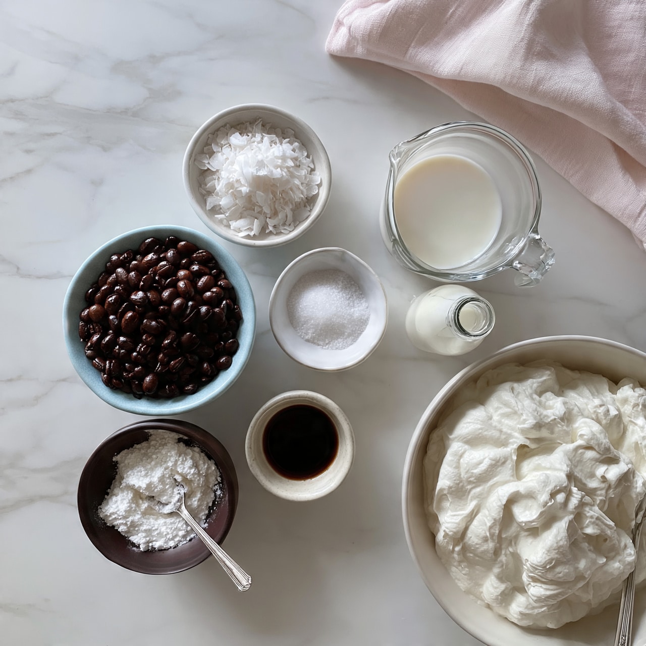 square image The image shows several small bowls and containers arranged on a white marbled surface. In the center, there is a light blue bowl filled with dark brown coffee beans, showing a shiny texture. Next to it, there are smaller white bowls containing white coconut flakes and white salt, and a small bowl with dark brown vanilla extract. A dark brown bowl holds white powder with a silver spoon resting inside. There is a clear glass measuring cup filled with a creamy white liquid situated near a small glass bottle of milk. In the bottom right corner, a large white bowl contains thick white whipped cream with a silver spoon inside. A pale pink cloth is placed in the top right corner near the measuring cup. Photo taken with an iphone --ar 4:5 --v 7
