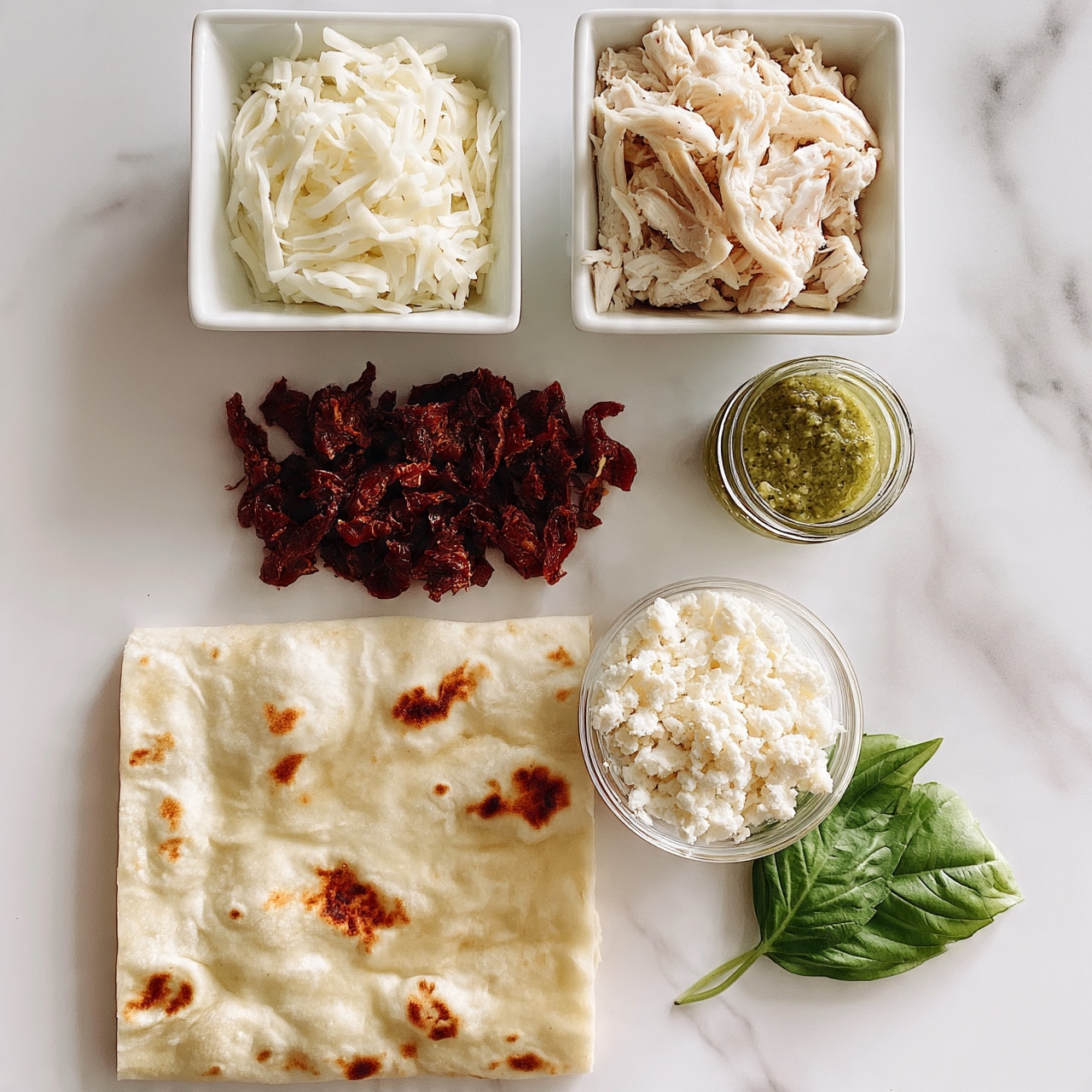 square image The image shows ingredients neatly placed on a white marbled surface. In the top row, two small white square bowls hold shredded white cheese on the left and shredded cooked chicken on the right. Below them, there is a pile of dark red sun-dried tomatoes on the left and a small glass jar of green pesto sauce on the right. Next to these, slightly lower, there is a small glass bowl filled with white crumbled cheese. At the bottom left of the image, there is a large rectangular flatbread with light brown charred spots. To the right of the bowl with crumbled cheese, there is a fresh green basil sprig. Photo taken with an iphone --ar 4:5 --v 7