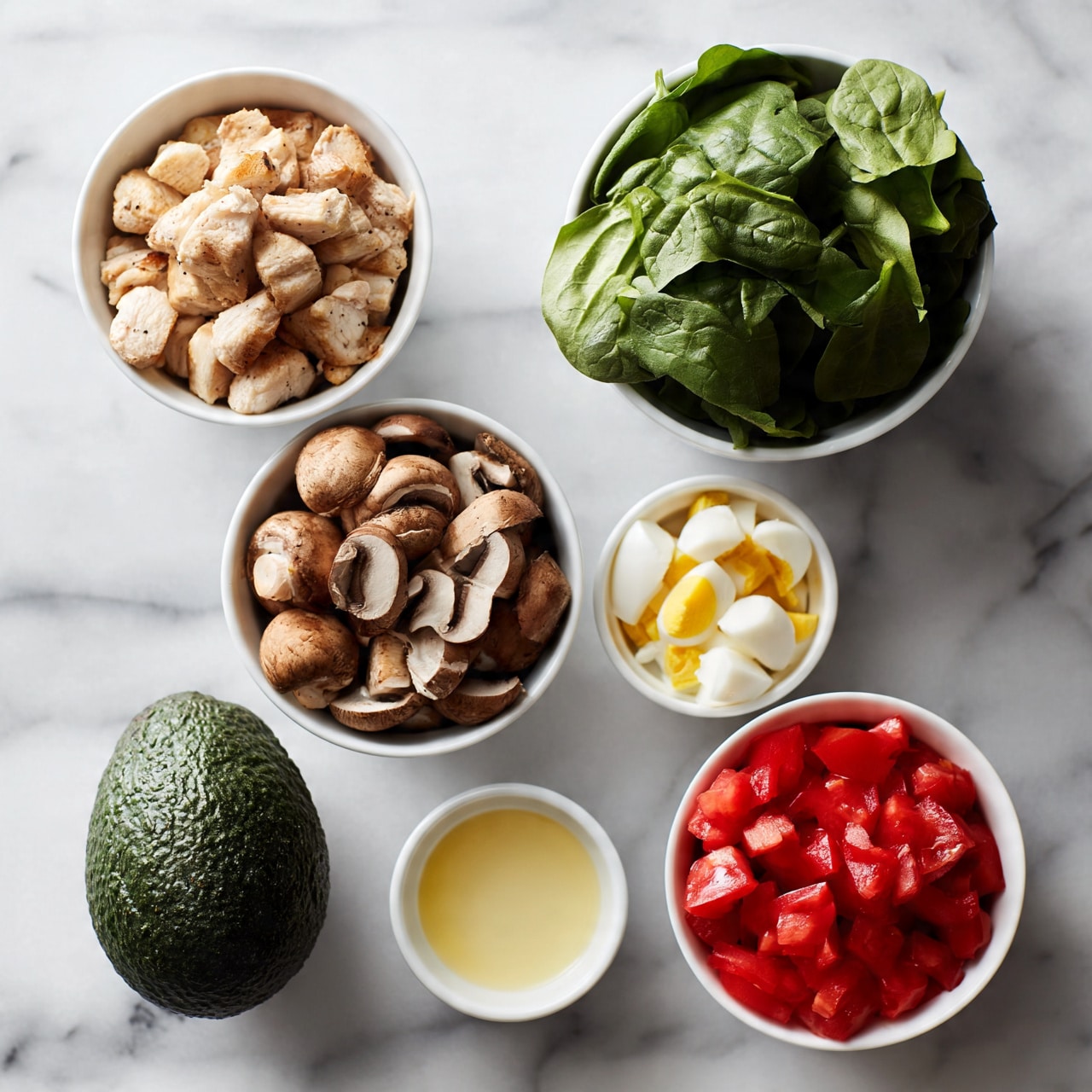 square image The image shows seven white bowls and one whole avocado arranged on a white marbled surface. In the top left, a white bowl holds chopped light brown grilled chicken pieces. To its right, a white bowl is filled with fresh green spinach leaves. Below the chicken, a white bowl contains sliced brown mushrooms. Next to the mushrooms, a small white bowl has diced white and yellow hard-boiled eggs. To the right of the eggs, a white bowl is filled with chopped red tomatoes. At the bottom center, there is a small white bowl with a light yellow dressing or sauce. The whole dark green, rough-skinned avocado is placed to the left of the dressing bowl. photo taken with an iphone --ar 4:5 --v 7