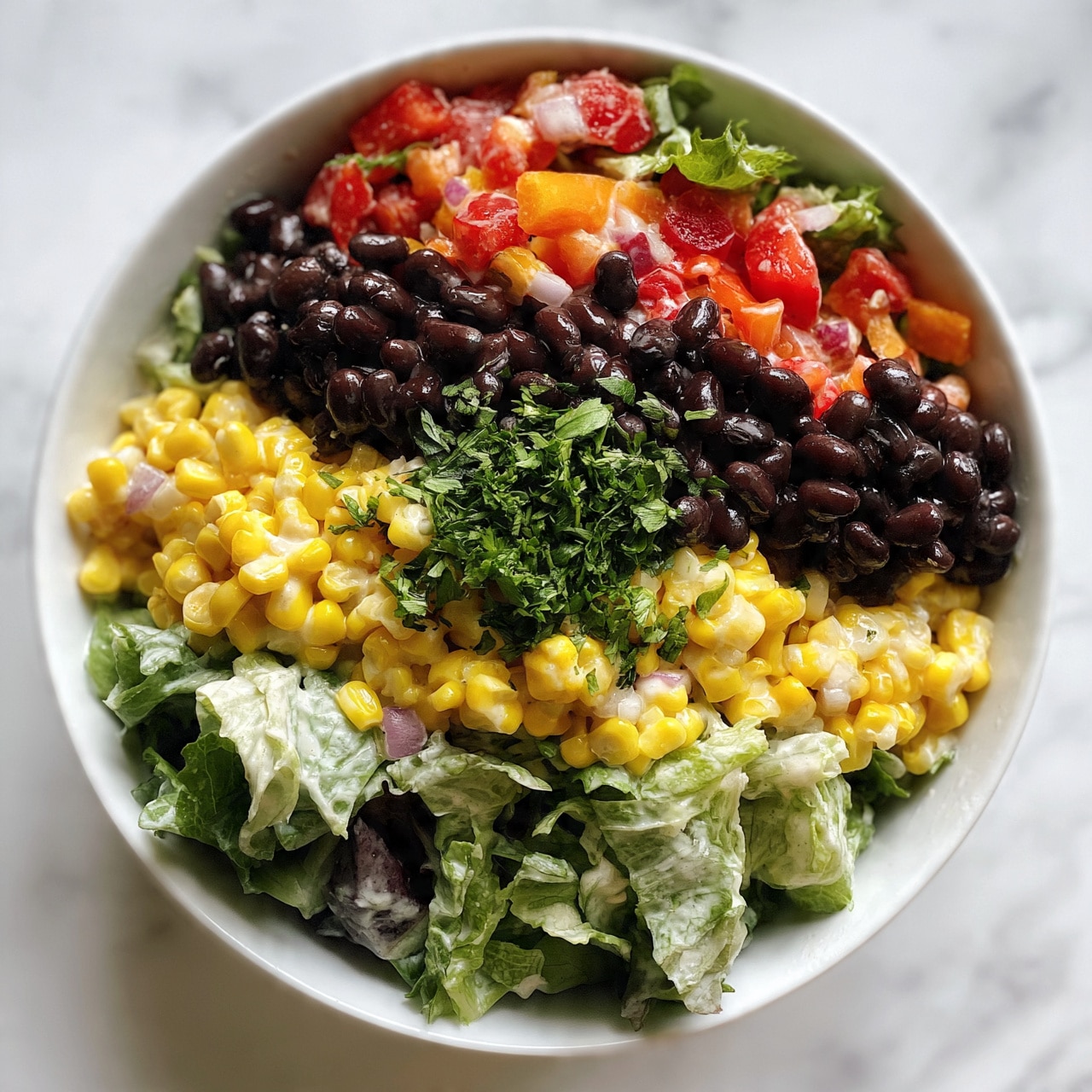 square image A white bowl filled with a colorful salad that has three main layers visible: black beans with a shiny smooth texture, bright yellow corn kernels, and fresh mixed greens with a slightly rough leafy texture. Red and orange bell pepper pieces add extra color, along with small bits of pale purple onion scattered throughout. The salad is topped with finely chopped fresh green herbs, all sitting on a creamy dressing that lightly coats the ingredients. The bowl is placed on a white marbled surface. photo taken with an iphone --ar 4:5 --v 7