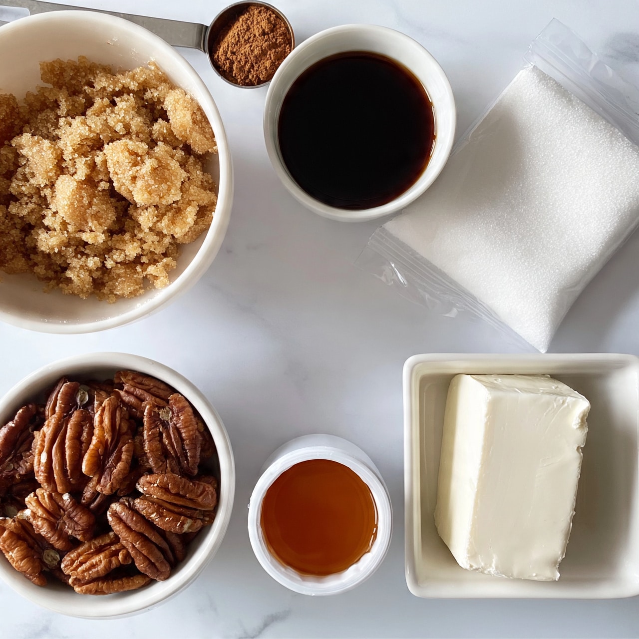 square image A top view shows six separate white bowls or containers arranged on a white marbled surface. The largest bowl at the top left holds crumbled light brown sugar. To its right is a small bowl filled with thick, dark syrup. Next to these, a clear bag filled with white granulated sugar lies flat. Below, there is a white bowl filled with whole pecans showing rich brown shells, and next to it is a small white container holding amber thick honey. A rectangular white dish at the bottom right contains a solid block of cream cheese with a smooth texture. A metal measuring spoon filled with ground cinnamon rests near the top left area. The overall image is bright and has a clean look. photo taken with an iphone --ar 4:5 --v 7