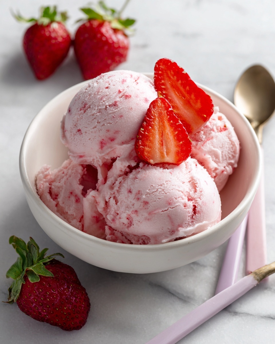 A small white bowl filled with smooth, light pink strawberry ice cream, topped with two bright red fresh strawberry halves placed on top. The bowl is set on a white marbled surface, with three whole red strawberries with green leaves nearby on the side. Two pastel spoons, one pink and one light purple, lie next to the bowl. The pink strawberry ice cream looks creamy and soft, with tiny red specks of strawberry throughout the texture. Photo taken with an iphone --ar 4:5 --v 7