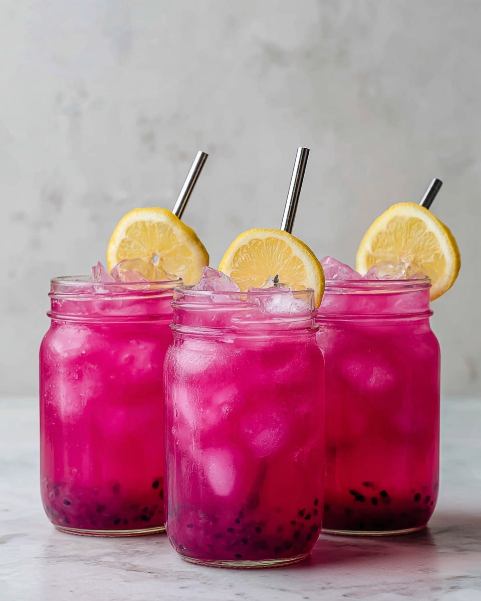 Three clear glass jars filled with bright pink drink and ice cubes are set side by side on a white marbled surface. Each jar has a slice of yellow lemon placed on its rim. The drink looks cold and refreshing, with small dark seeds settled at the bottom of each jar. The jar in the middle has a shiny metal straw while the other two jars do not have straws. The background is a white marbled texture. photo taken with an iphone --ar 4:5 --v 7