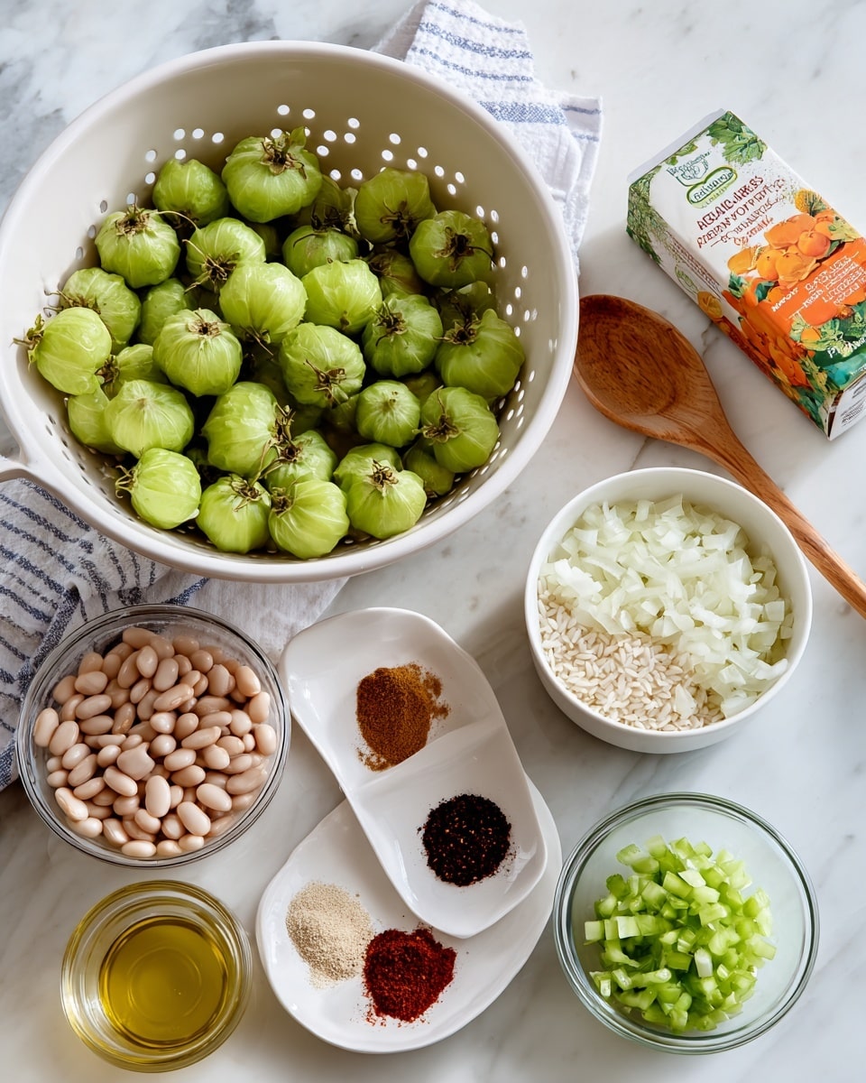 The image shows a white colander filled with green tomatillos with a few husks peeking out from the sides at the top left. Below the colander, there are two clear glass bowls, one with chopped white onions and the other with uncooked rice. To the right of these bowls, a small white plate holds different powdered spices in separate piles, including dark red, black, tan, and light brown colors. Above the spices, a white bowl is filled with light pink beans soaking in water, and next to it is a wooden spoon resting on the white marbled surface. To the far right, a clear glass bowl contains chopped green peppers. Behind the beans, there is a carton of vegetable broth with an orange and green design. A small clear container with light olive oil is placed in front of the chopped peppers. All items rest on a white marbled background with a folded white and blue striped cloth towel visible behind the colander. Photo taken with an iphone --ar 4:5 --v 7