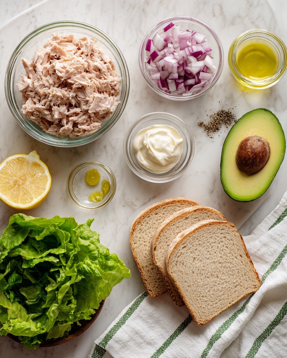 The image shows ingredients for a tuna salad sandwich arranged neatly on a white marbled surface. There is a clear glass bowl filled with light pinkish shredded tuna on the left. Beside it, a small glass bowl holds chopped red and white onions. Another small clear bowl contains a dollop of white creamy mayo. A small glass bowl with ground black pepper sits next to it. On the right, there are three slices of light brown bread with a porous texture on a white marbled surface. A fresh half avocado with its green inner flesh and dark outer skin lies beside some bright green leafy lettuce. A halved lemon and a small glass bowl with light yellow lemon juice are placed on a white cloth with green stripes near the top center. A half slice of red onion, with two small drops of yellow lemon juice on it, rests near the bread. The photo taken with an iphone --ar 4:5 --v 7