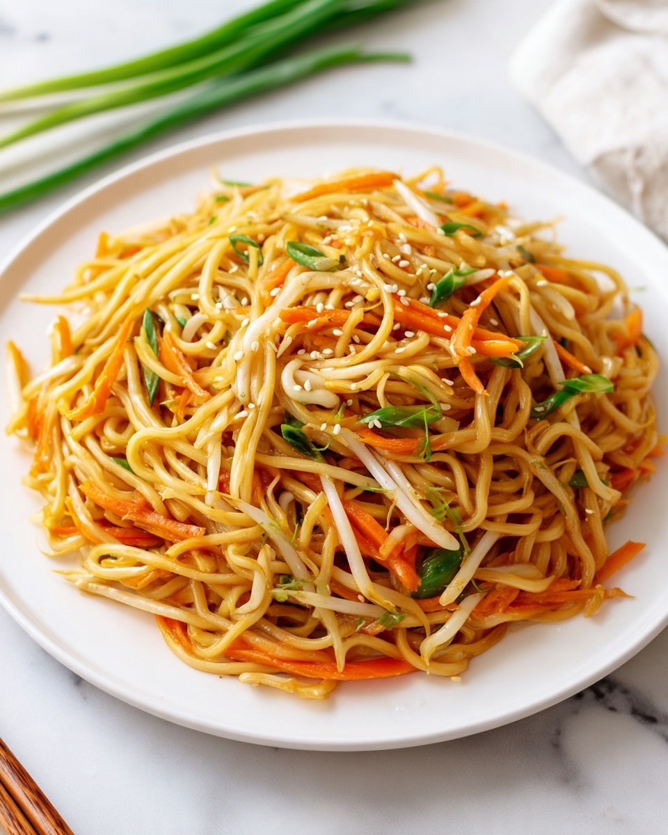 A white plate filled with a single layer of stir-fried noodles that are light brown and slightly glossy. Mixed in the noodles are thin, long slices of orange carrots, green scallion pieces, and pale bean sprouts scattered evenly. The dish is sprinkled with small white sesame seeds across the top. The plate is placed on a white marbled surface with some green scallions and chopsticks nearby. photo taken with an iphone --ar 4:5 --v 7