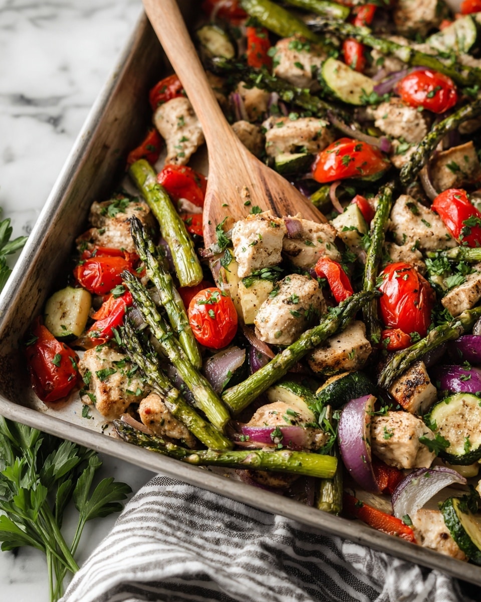 A close-up view of a large rectangular metal pan filled with roasted pieces of white meat mixed with bright green asparagus spears, halved red cherry tomatoes, small slices of green zucchini, chunks of red bell pepper, and pieces of purple onion, all sprinkled with fresh green parsley on top. A wooden spatula is partially inside the pan, lifting some of the food. The pan sits on a white marbled surface, next to a bunch of fresh parsley and a striped gray and white cloth. photo taken with an iphone --ar 4:5 --v 7