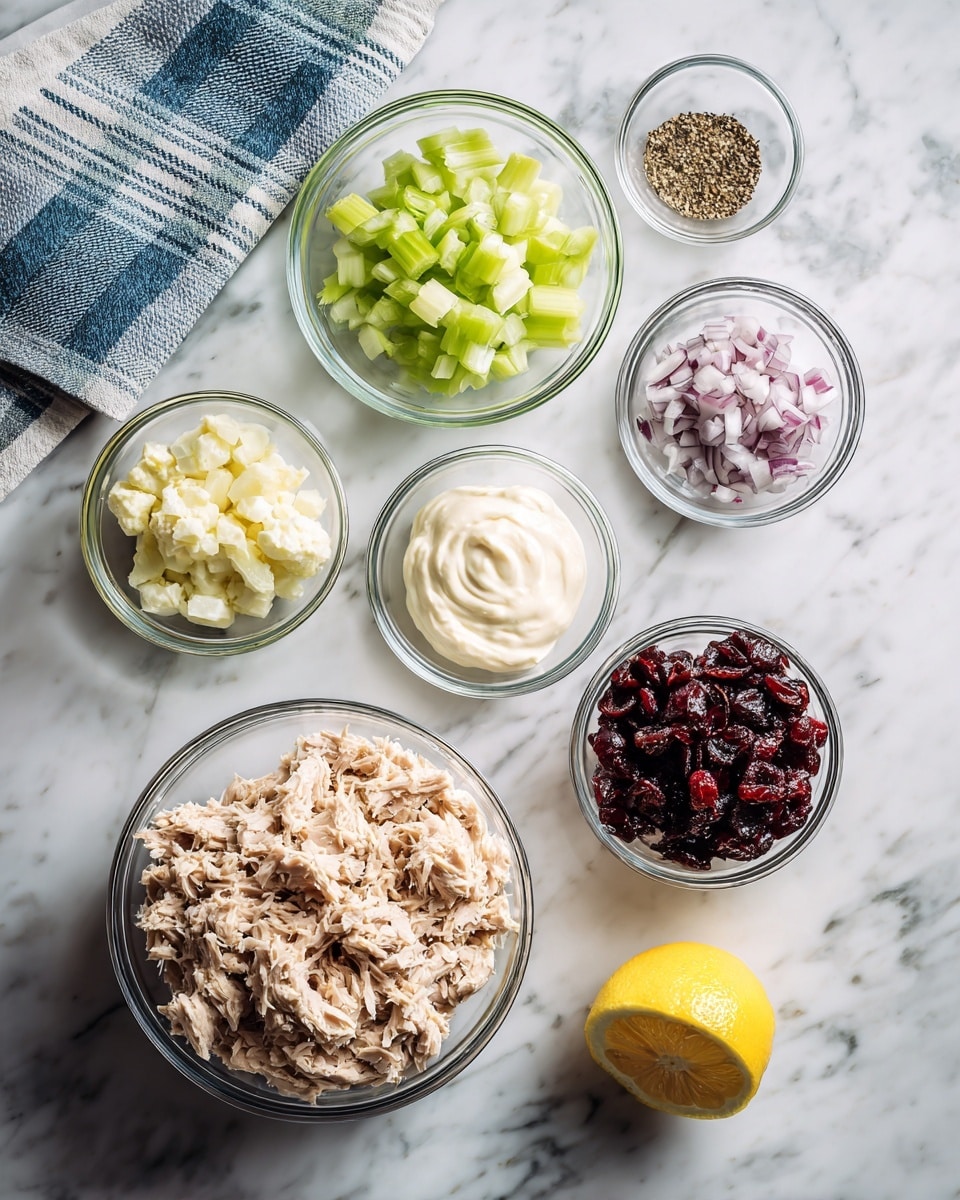 The image shows a white marbled surface with seven clear glass bowls arranged neatly. The largest bowl in the bottom left is filled with light beige shredded tuna. Above it is a smaller bowl with diced pale green celery. To the right of the celery is a small bowl with finely chopped light purple shallots. Beside the shallots is a bowl of dark red dried cranberries. Above the tuna bowl is a bowl with thick white mayonnaise. Next to the mayonnaise, slightly higher, is a small bowl containing one lemon wedge. In the top right corner, there is a very small bowl with ground black pepper. A blue and white striped cloth is folded on the white marbled surface near the top left. Photo taken with an iphone --ar 4:5 --v 7