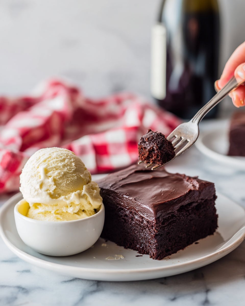 A white plate holds a thick, square piece of dark chocolate cake with a smooth, shiny layer of dark chocolate frosting on top. Next to the cake is a small white bowl filled with a scoop of pale yellow vanilla ice cream that shows soft texture and some melt marks. A woman's hand is holding a fork with a small piece of the dark chocolate cake on it above the plate. The background shows a red and white checkered cloth and a blurred dark bottle, all on a white marbled surface. photo taken with an iphone --ar 4:5 --v 7