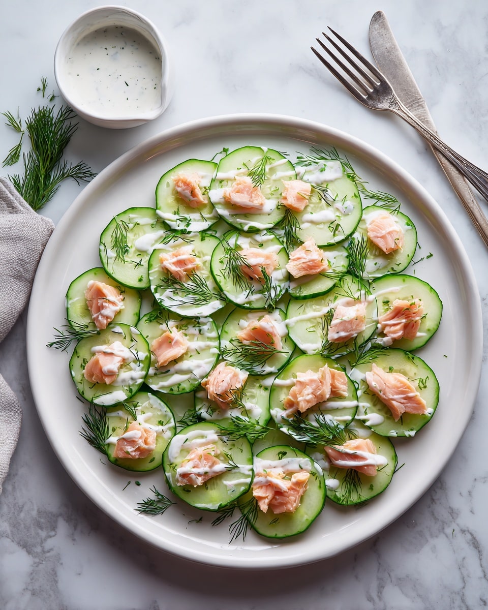 A round white plate filled with a thin layer of light green cucumber slices arranged side by side to cover the plate surface, topped with small pieces of light pink smoked salmon scattered evenly, drizzled with thin white sauce lines, and garnished with sprigs of green dill. Next to the plate, there is a small white bowl with white sauce and a silver fork resting on a white marbled surface. Photo taken with an iphone --ar 4:5 --v 7