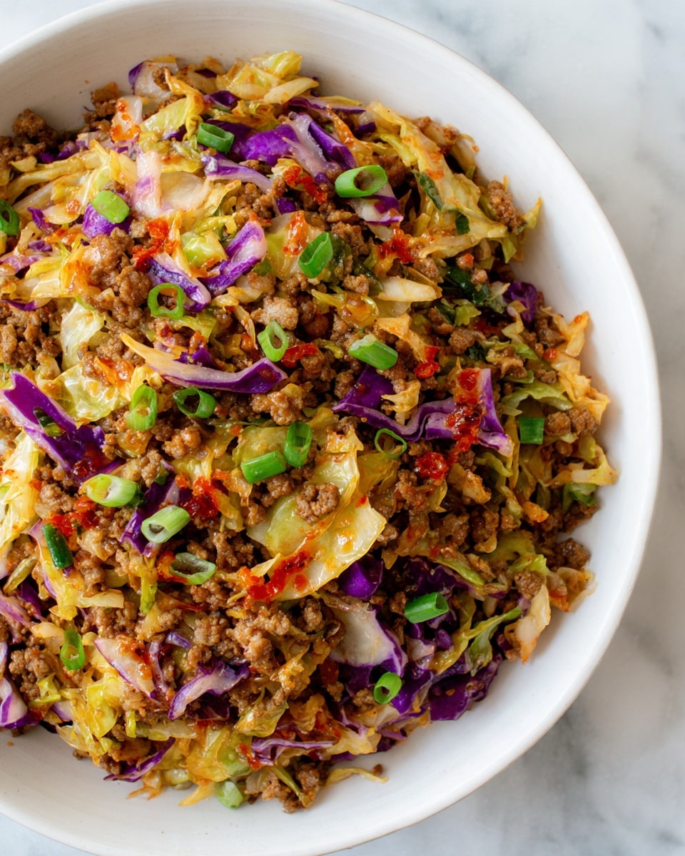 A close-up of a white bowl filled with a mix of cooked ground meat and shredded cabbage. The ground meat is brown with a slightly crumbly texture, evenly mixed with both light yellow and light purple cabbage shreds. Small green onion slices are scattered on top, adding a fresh green touch. There are also small drops of red sauce dotting the mixture. The bowl sits on a white marbled surface, showing the colors and textures of the food clearly. photo taken with an iphone --ar 4:5 --v 7