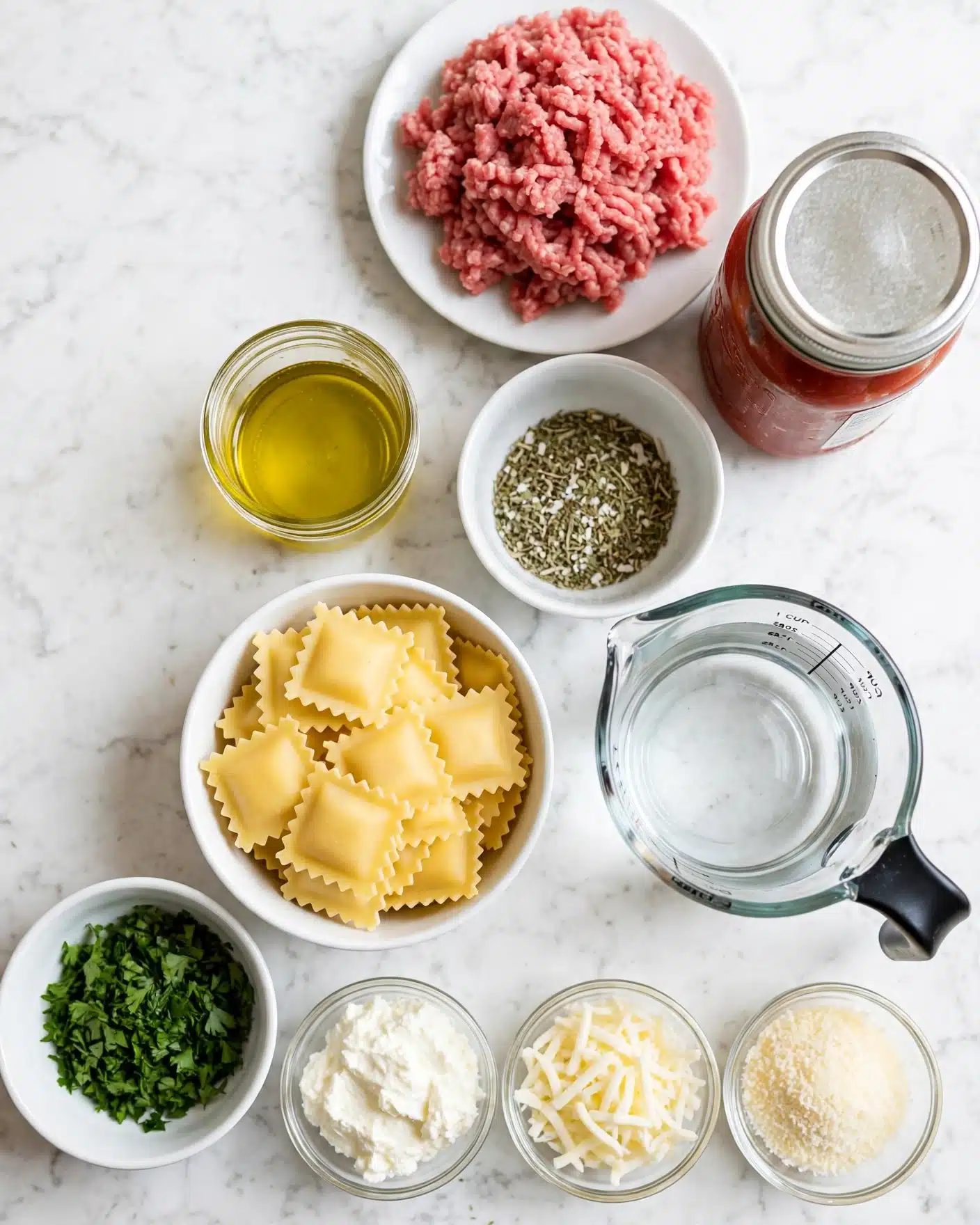 Easy One-Pan Lasagna Recipe 4 square image The image shows ingredients neatly arranged on a white marbled surface. Starting from the top right, there is a white plate filled with raw ground meat in soft pink color and a jar of red tomato sauce with a silver lid placed next to it. Below these, a small white bowl holds a mixture of white and green dried herbs and spices, while to the left, a small glass container is filled with yellow olive oil. Towards the bottom center, a white bowl contains flat yellow pasta squares with ruffled edges. To the right, a clear measuring cup with a black handle holds water. At the bottom left, there is a small white bowl filled with fresh chopped green herbs, followed by three small glass bowls containing white ricotta cheese, shredded white mozzarella cheese, and grated pale yellow Parmesan cheese laid out in a row photo taken with an iphone --ar 4:5 --v 7